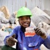 A Karo Enterprise employee holds an empty red and white RUTF sachet, which will be recycled into eco-friendly bricks and paving stones.