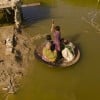 A boy transports people on his curry frying pan across the flooded waters in Jhuddo town of District Mirpurkhas of Sindh, Pakistan, following the devastating floods in 2022.
