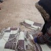 Samira* tears up a worn out-mat to burn amid the harsh winter in Syria