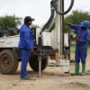 Two men with a machine which is boring a hole into the ground