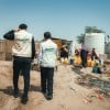 Concern’s health staff and the Country Director Victor Moses visit a displacement camp in Yemen, with people filling a water tank in the background