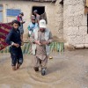 Concern staff member walking through flooded garden of a home with family members behind him