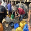 People gather to fill containers with clean water from a tank. 