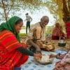 Concern Communications Officer Kalkidan Jabir shares a meal with Hussein Abdulahi Hussein and his wife Nadifa Yusuf and their family in Alloley Kebele, Dollo Bay District in the Somali Region of Ethiopia. Hussein leads a group of 45 farmers who are part of an agriculture group supported by the Hannano Programme. With this support, they received improved variety of seeds, a generator, fuel, water pumps, and training.
