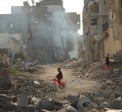 Child on tricycle cycles through destroyed buildings in Gaza