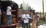 Concern staff organising the distribution of new tent kits (including wood, plastic sheeting etc) to families whose homes were recently burnt down. The tents are going to be built on this field, in Northern Lebanon. Photograph by Mary Turner/Panos Pictures for Concern Worldwide