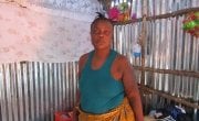 Woman stands in her new home in Kroo Bay