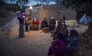 A group of Syrian refugees outside their tents at night.