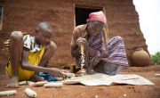 13 year old Abinet, helps his mother, Workinesh Alto, to strip maize cobs in front of the new family home.