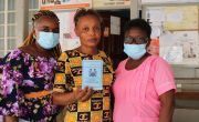 Three women with masks holding vaccination certs
