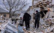 Four people searching through rubble of destroyed house