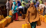 Somali woman walking to a water truck carrying containers to be filled