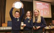 Two girls and a boy smile as they hold their awards after winning the Concern  Primary Schools Debate Final 2022
