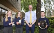 Two girls and a boy smile as they hold their awards after winning the Concern Primary Schools Debate Final 2022