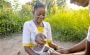 Young Congolese mother holding her baby while he is screened for malnutrition using MUAC tape