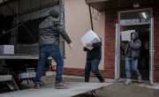 Illya* a person who has been displaced by conflict in Ukraine now volunteers at a community hub. Here, he is moving food kits as they are prepared for distribution. Photo: Simona Supino