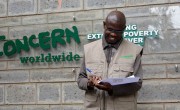 Concern Country Financial Controller smiles while signing piece of paper outside Concern office