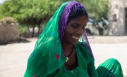 Jamna, wearing green and purple veil, smiling and looking at ground