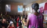 Children in classroom in Ethiopia sitting on floor and raising hands for teacher