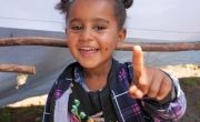 Young girl in Ethiopia smiling and pointing in camera