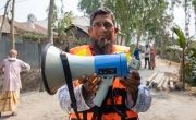 A man wearing an orange lifejacket holds a megaphone