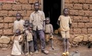 Samuel Ndagijimana and five of his children standing outside brick building