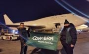 Concern staff holding in front of airplane carrying aid 