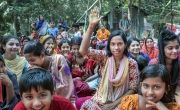 Villagers of Sarkarpara gathered in Bangladesh, with one woman raising hand