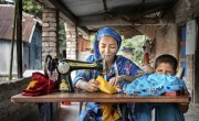 Halima Begum sewing clothes with her son