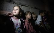 Ukrainian children wait in their school's bomb shelter for an air raid to end. Dark and damp, the basement still needs renovation