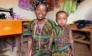 Alexia Mukashyaka (40) and her daughter Brigit (2) at her tailoring shop in Mugombwa, Gisagara. Alexia was selected for the Graduation Programme in 2019. After investing in a sewing machine, she started up a successful tailoring business, making on average 20 outfits for women each week. She plans to expand and eventually open a hairdressing salon, and is currently receiving lessons on hair styling. (Photo: Eugene Ikua/Concern Worldwide)