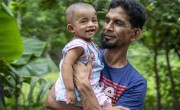 Md. Helal Kha (42) gently holds his 11-month-old son, Md. Amzad Hossen. 