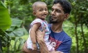 Md. Helal Kha (42) gently holds his 11-month-old son, Md. Amzad Hossen.