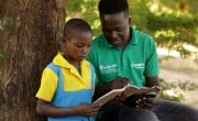 Lucia Bisenti (10) reading a school book with Concern Programme Support Officer Alan Milanzie in Mchiliko, Nsanje.