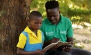 Lucia Bisenti (10) reading a school book with Concern Programme Support Officer Alan Milanzie in Mchiliko, Nsanje.
