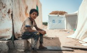 A young boy sits outside a tent in an IDP camp in Yemen.
