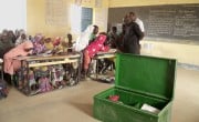 Seydou*, a preschool and primary education inspector (in black) looks at one of the literacy trunks provided to a school in Tahoua as part of Concern's Learning Together (Apprendre Ensemble) programme. Photo: Concern Worldwide