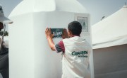 Concern’s WASH officer posting Concern’s sticker on latrines installed by Concern in Al-Salam IDP site, Dar Saad district, Aden Governorate