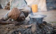 A woman starts a cooking fire at the temporary settlement built on Kok Island in the swamps of Unity State.