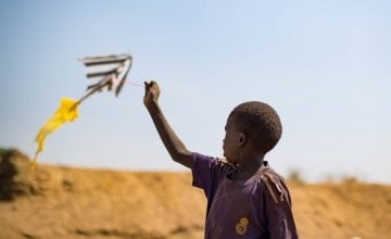 A child flies a home made kite. Pictured in 2018 on the streets of Juba's PoC, South Sudan. 