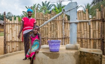Irene with her daughter Lucy (8) and their new water pump. Photo: Gavin Douglas/Concern Worldwide.