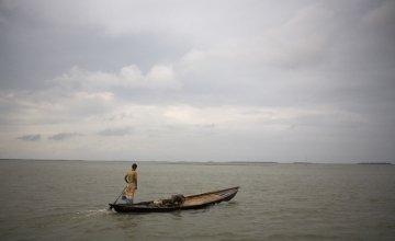 A lone boatman travels accross the Haor flood plains of North East Bangladesh. 