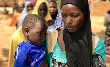 Mum-of-four Tsahara Maidagi (27) and her 19-month-old son Mamane wait to receive an emergency monthly money transfer and fortified flour at a Concern distribution in Sarkake, Tahoua. “The money helps our family. It is used mainly to buy food, like millet and vegetables for us to eat,” she said. Photographer: Darren Vaughan/ Concern Worldwide.