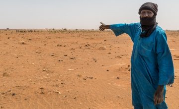 Mahamadou Islam Garmazaye is the Chief of Garmazaye village. He is pointing here to the arid land that has seen very poor harvests for the last five years. Photo: Apsatou Bagaya / Concern Worldwide.