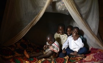 Brothers Salomon (3), David (6), Issa (10) and Selemani (13) in bed with their mosquito net. Photo: Chris de Bode / Concern Worldwide.