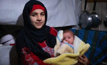 Wafdeh* (20) with her youngest daughter Rajaa* wrapped in a thermal blanket in their makeshift kitchen. Photo: Gavin Douglas/ Concern Worldwide.