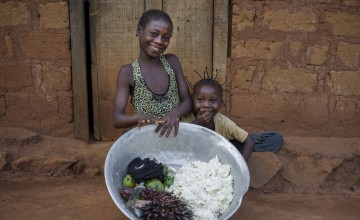 Patricia and friend Julie (9) with a bowl of mashed cassava, palm nuts, avocados, mushrooms and tomatoes which they bought for the family meal.