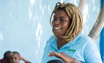 Jasmine listens as Woodson Marcelin tells a story during Children’s Parliament activities in Cité Soleil, Port au Prince. Photo: Kieran McConville/ Concern Worldwide.