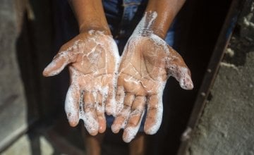 Rosette Mesalien 34 washes her hands with liquid soap she made with help from Concern in front of their home in Cite Soleil slum, a district of Port-au-Prince, Haiti.