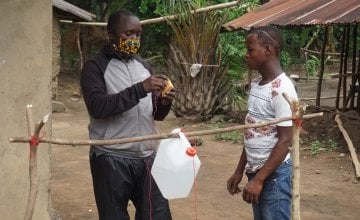 Alusine Baba Sesay (Left) a concern worldwide staff training a teen on construction of a local hand washing facility (TippyTap) after distributing soap and a water containers to households in the Tonkolili District, Sierra Leone. Photo: Mohamed Saidu Bah / Concern Worldwide.
